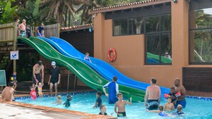 Une piscine avec un toboggan et une bouée de sauvetage fixée au mur.