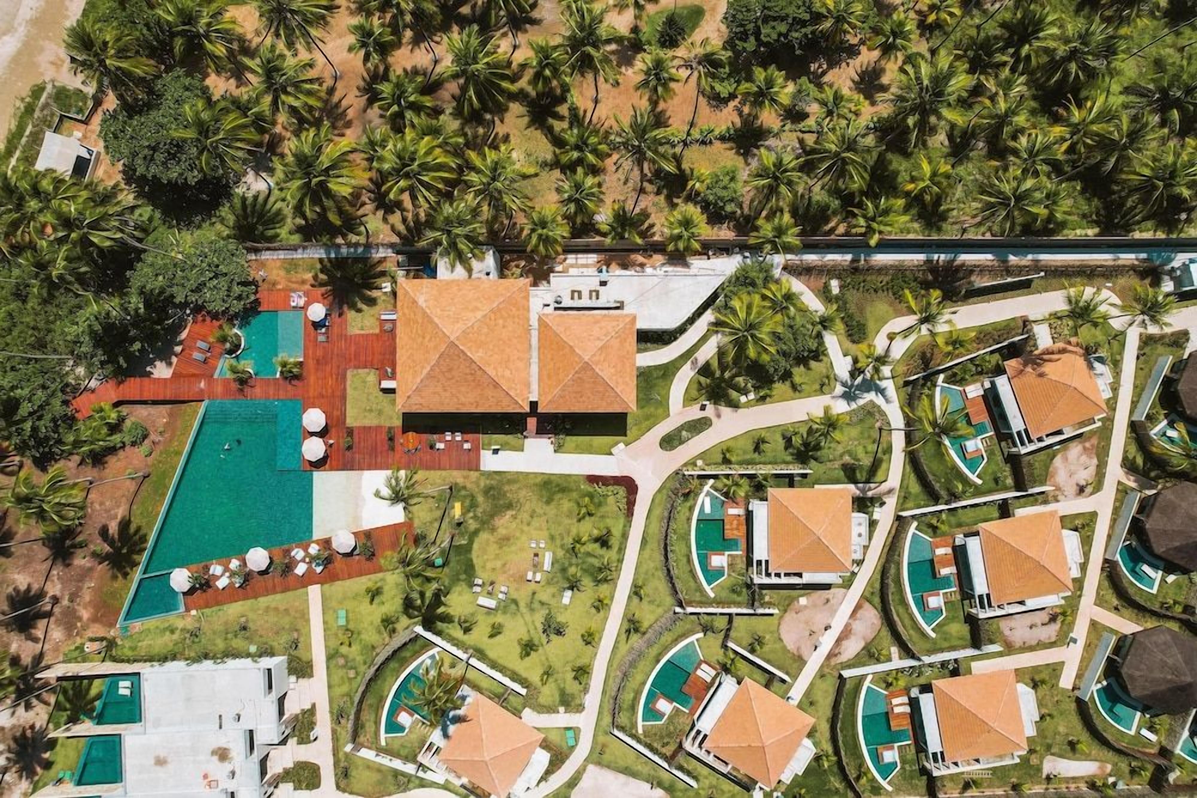 Vista aérea de um resort com várias piscinas, palmeiras e edifícios do resort.