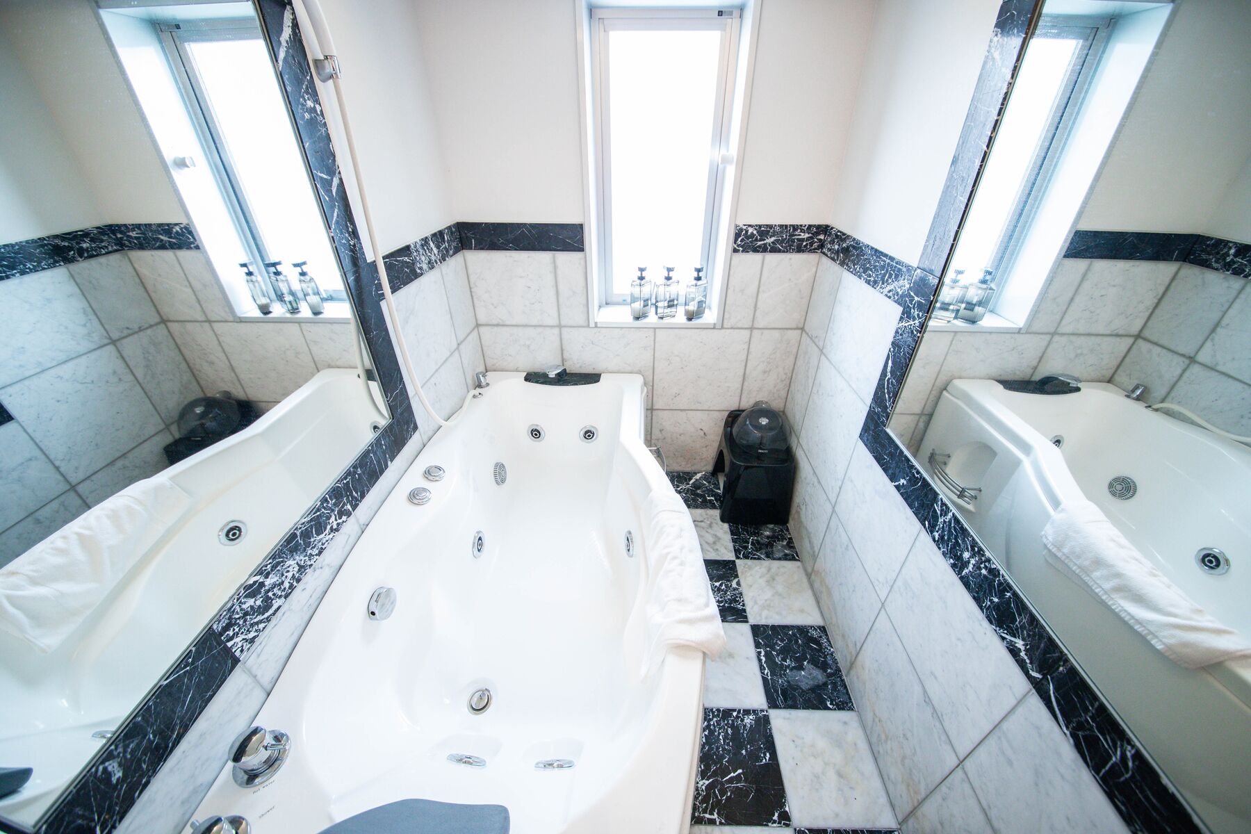 A bathroom with two separate tubs, a window, and a tiled floor.