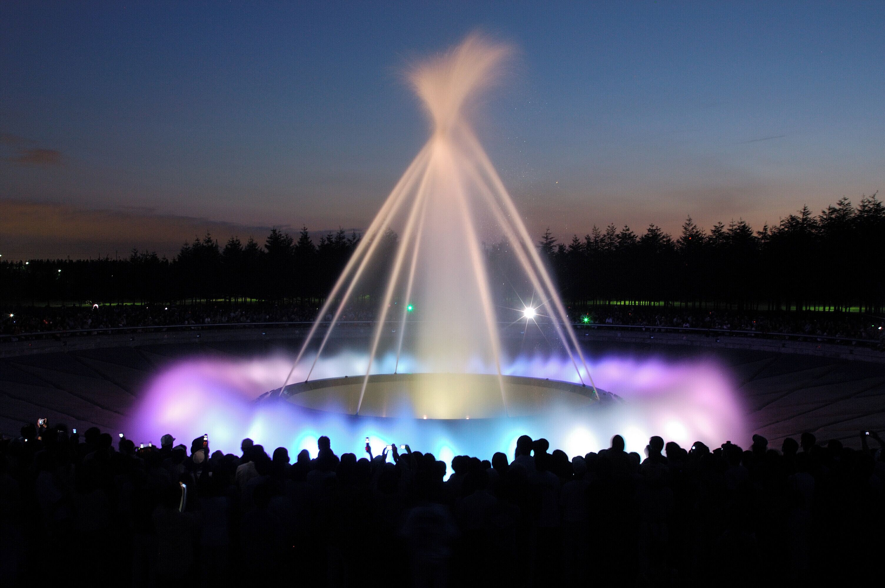 A large outdoor stadium with a central stage and a crowd of people.