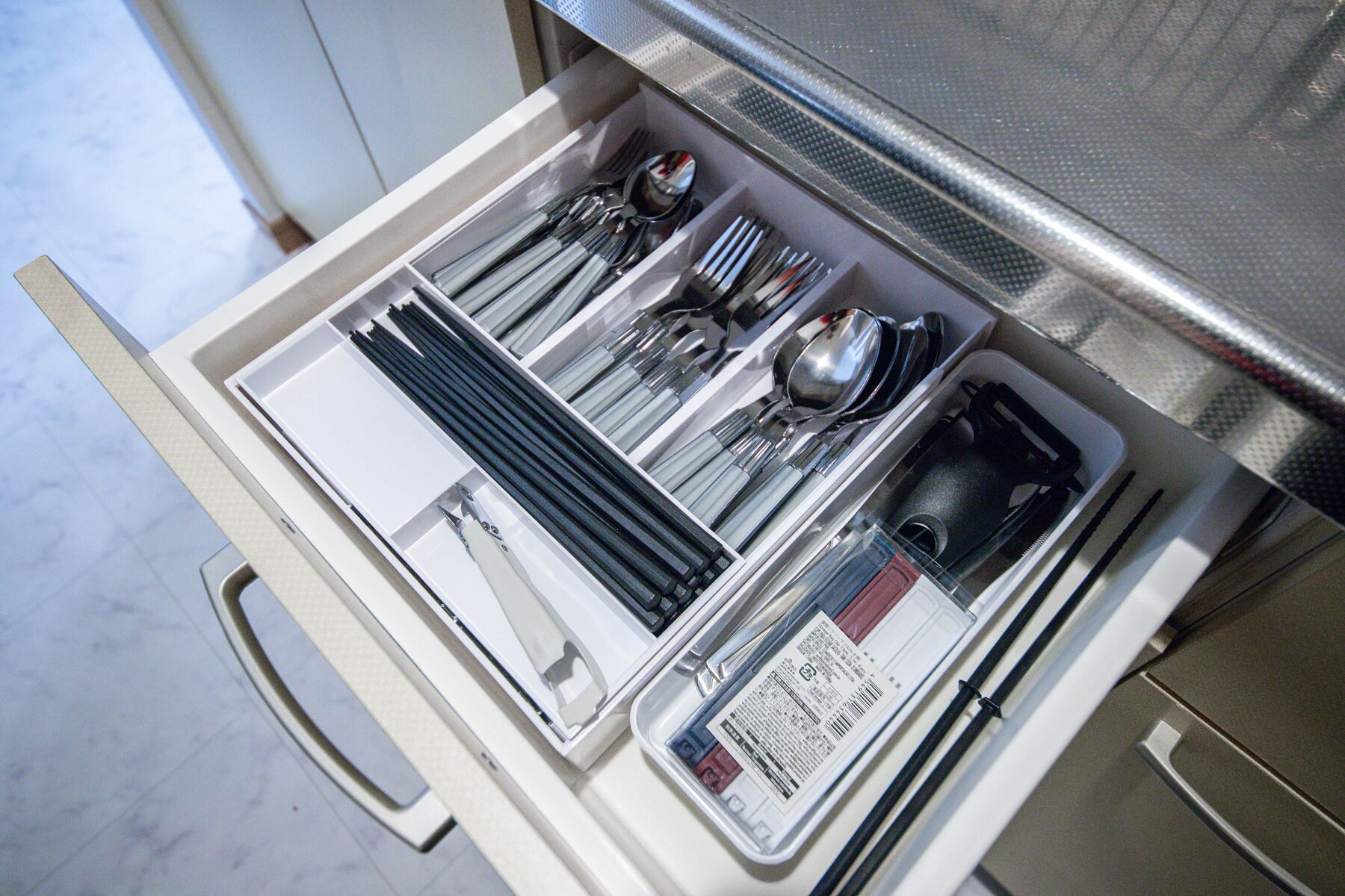 A drawer with neatly organized cutlery, including spoons, forks, and knives.