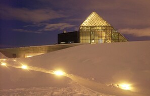 Paisatge cobert de neu amb un edifici piramidal il·luminat de nit.