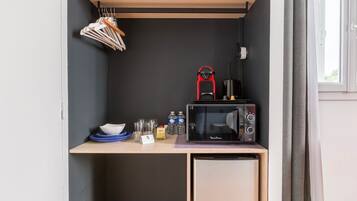 A compact kitchenette with a microwave, a small refrigerator, and a coffee maker.