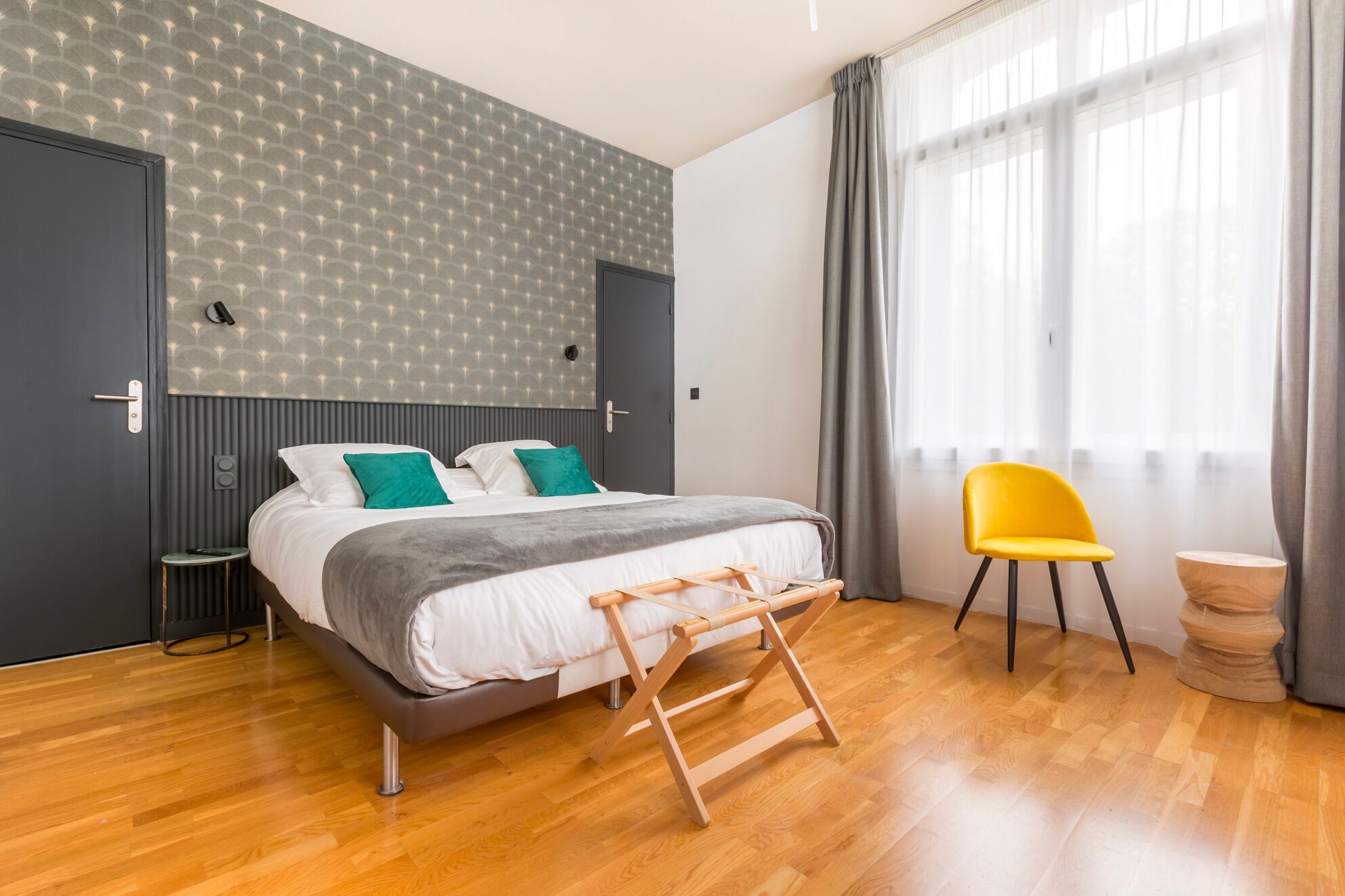 Quarto moderno com uma cama, escada de madeira, cadeira amarela e uma pequena mesa.