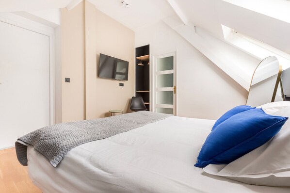 Un dormitorio moderno con cama, televisor y vestidor.