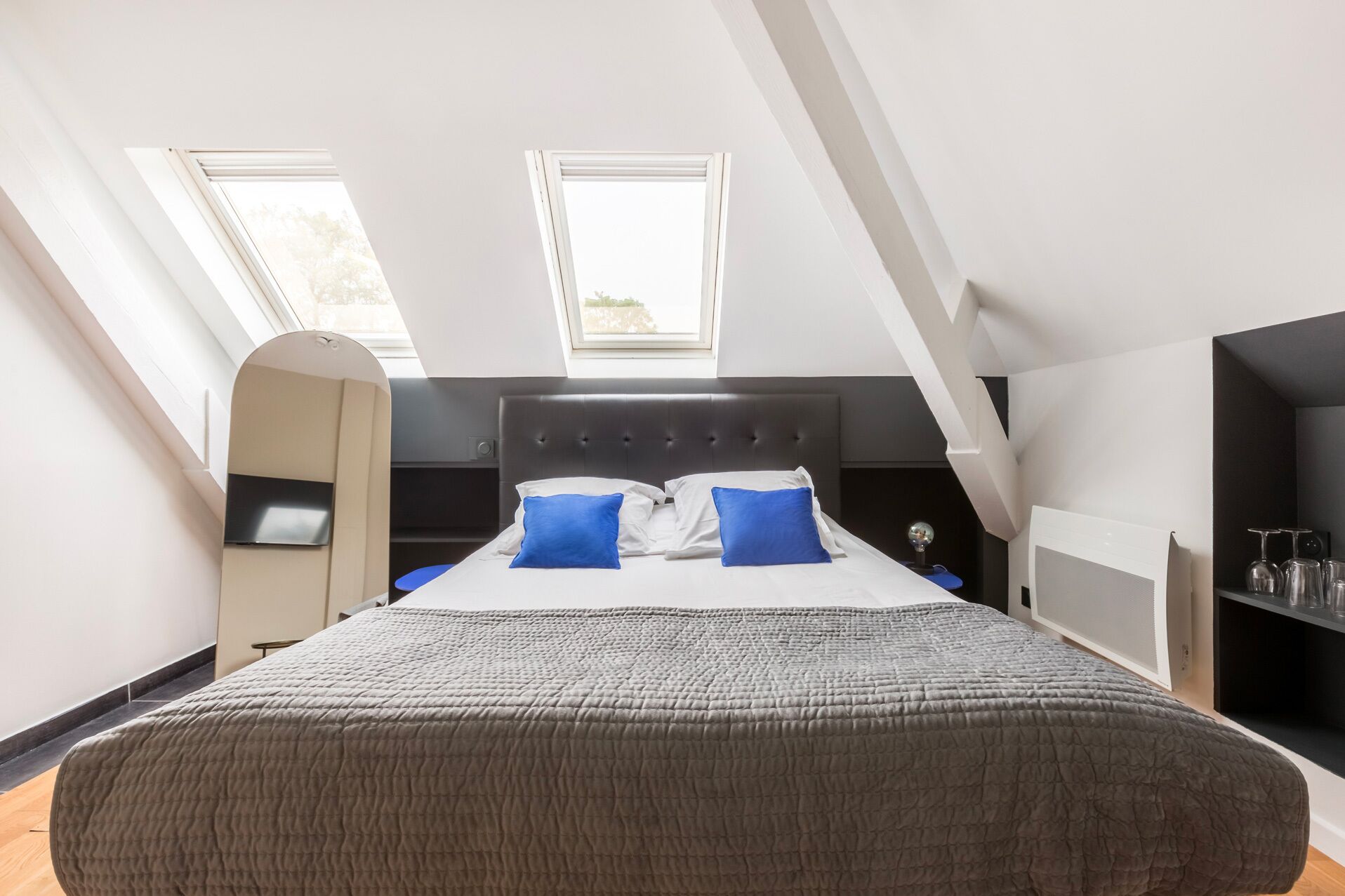 Un dormitorio con una cama grande, dos ventanas, cabecera negra y armario empotrado.