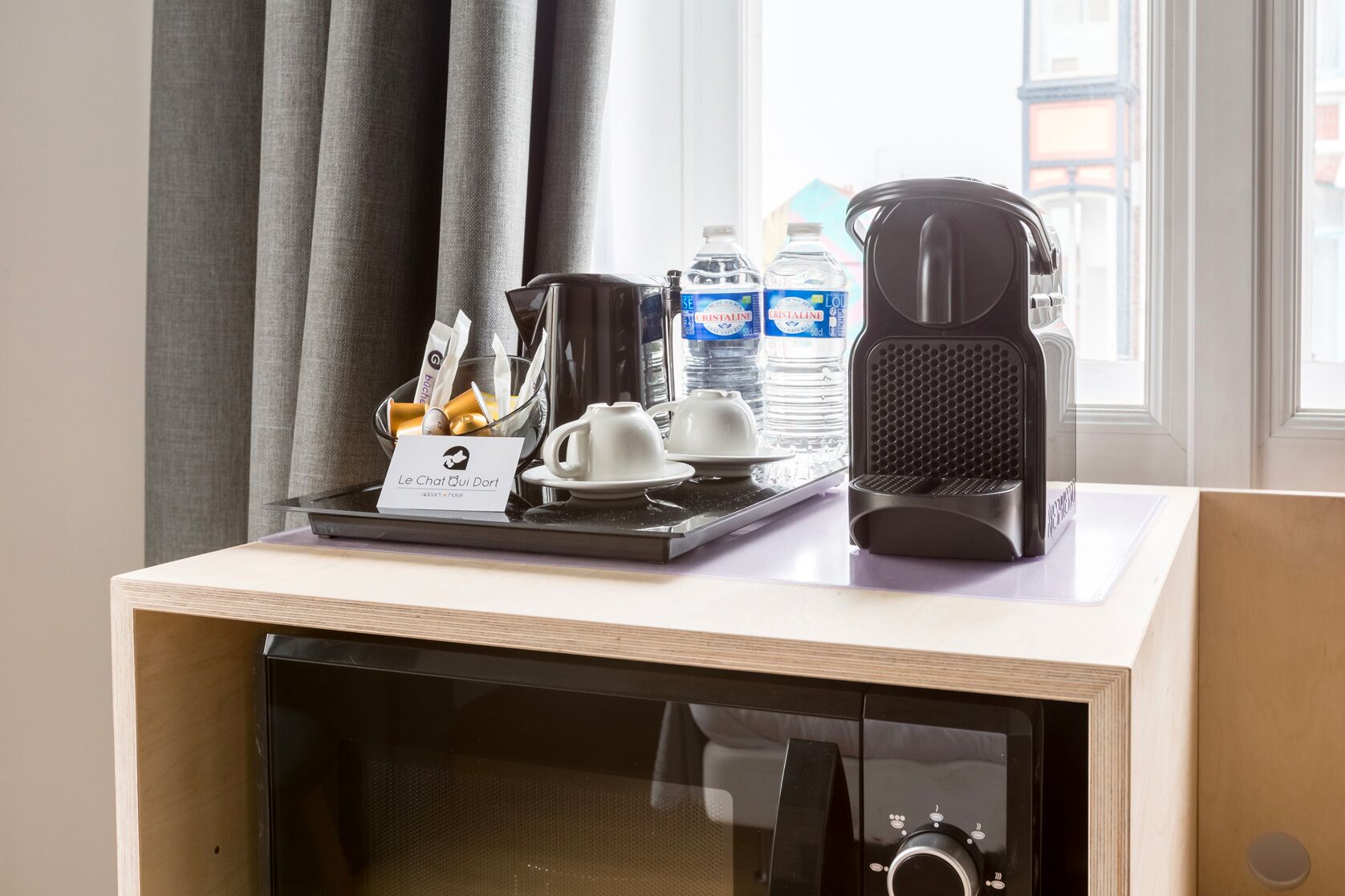 A hotel room with a breakfast tray, a coffee machine, and a water dispenser.