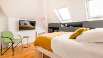 Een moderne hotelkamer met een bed, een groene stoel, een kleine tafel, een televisie en een dakraam.
