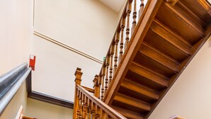 A wooden staircase with red carpeted steps and wooden balusters.