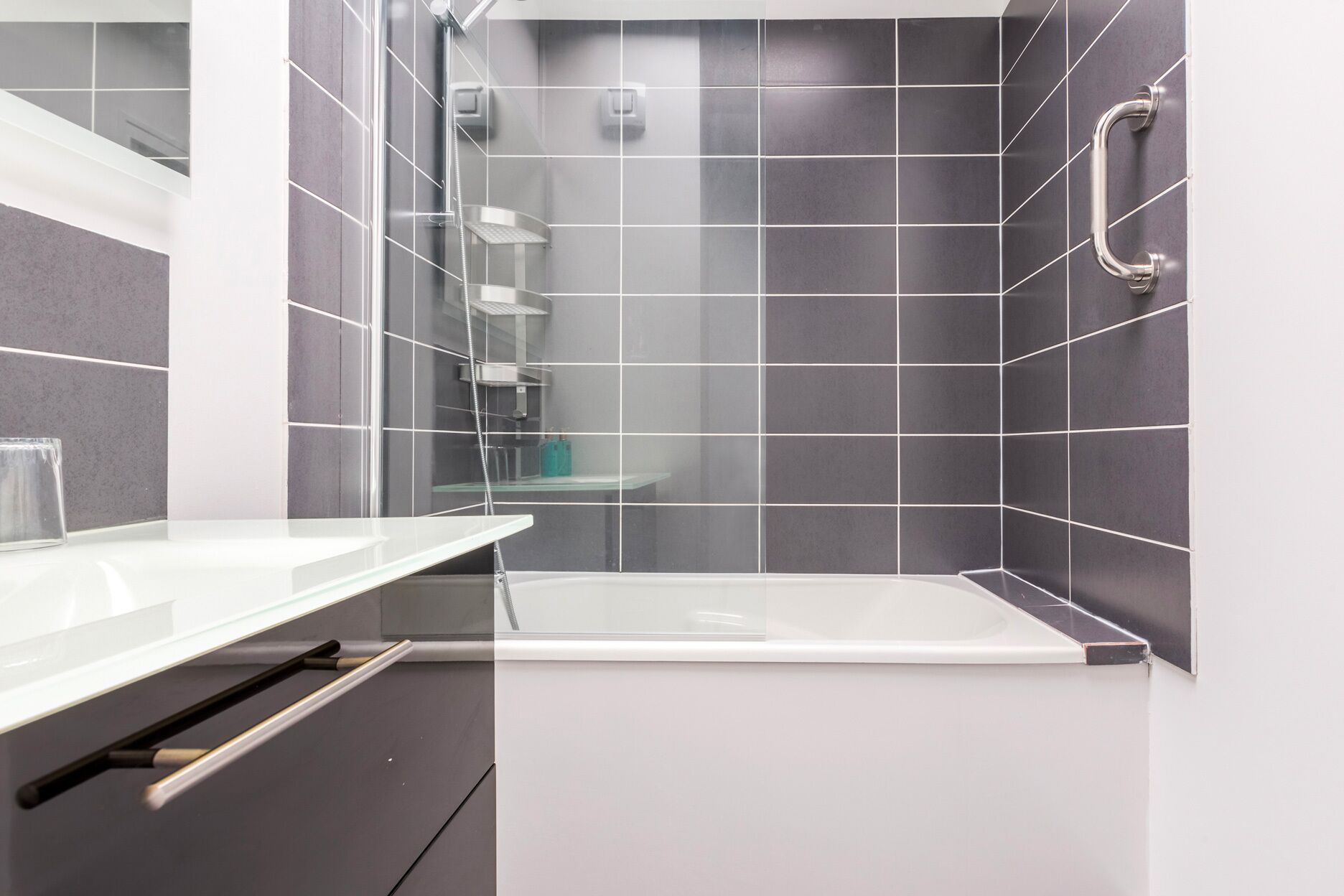 A modern bathroom with a glass shower enclosure, a bathtub, and a white sink.