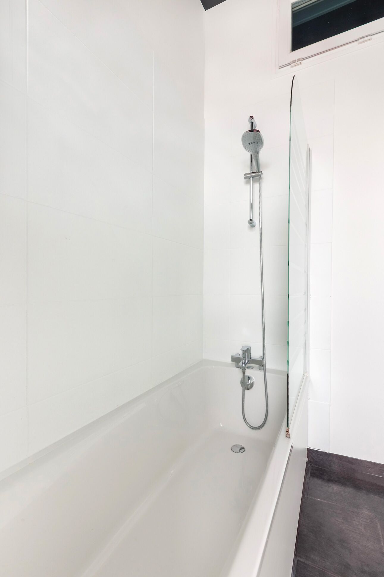 A modern bathroom with a bathtub, a showerhead, and a glass shower enclosure.