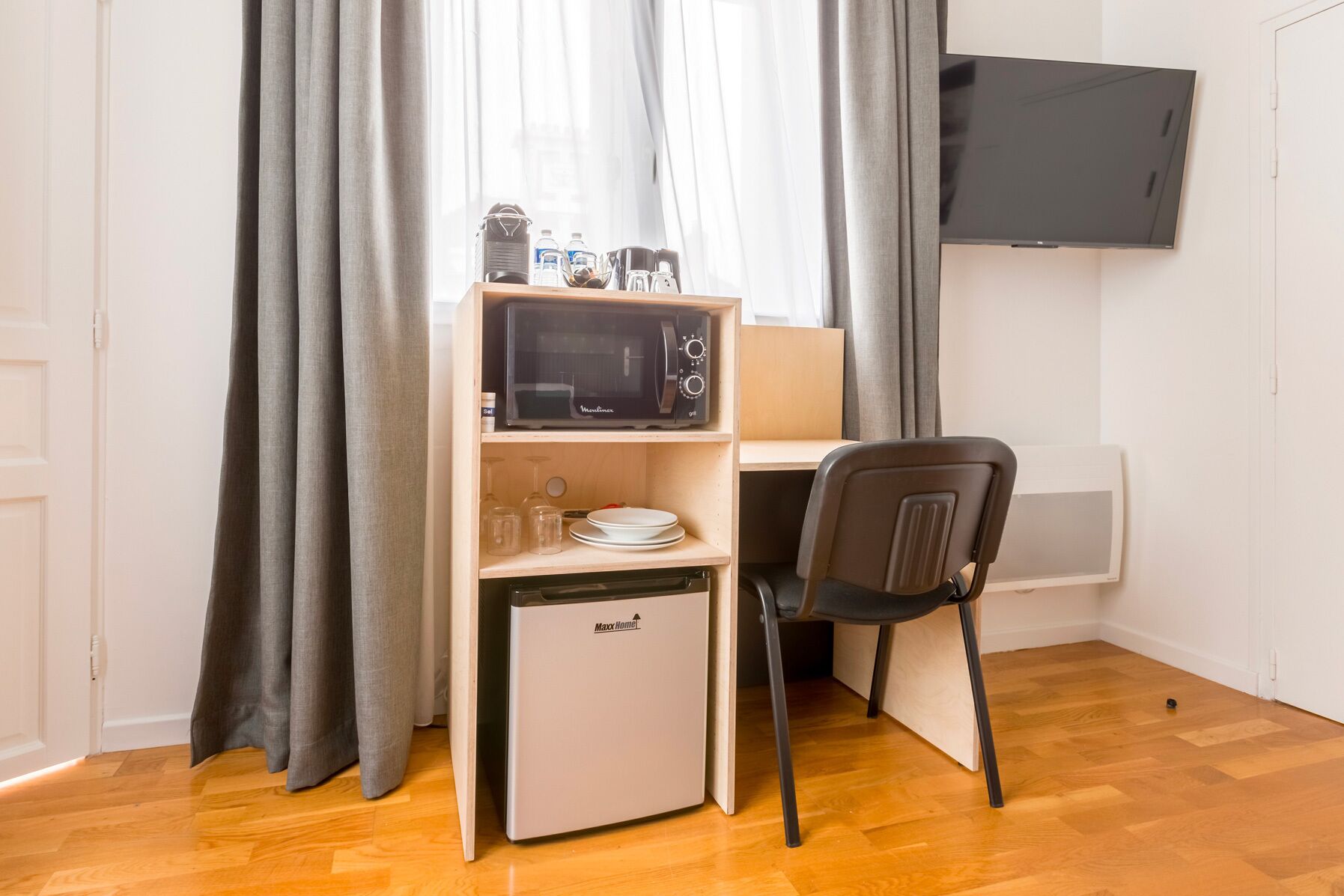 A compact kitchenette with a microwave, a small fridge, and a chair.