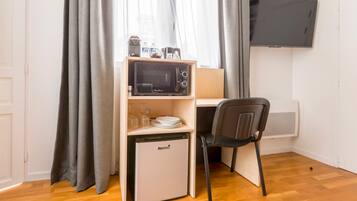 A compact kitchenette with a microwave, a small fridge, and a chair.