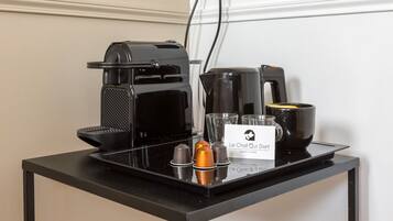 A coffee station with a coffee maker, a kettle, a mug, and a sign for "Le Chat Qui Dort" hotel.