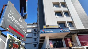 Un immeuble à plusieurs étages, sur lequel on peut voir une enseigne indiquant « Hôtel Golden Orchid », un restaurant Domino’s Pizza et une banderole annonçant la plus grande fête de Noël de l’année.