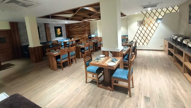 Un restaurant avec des meubles en bois, une grande table à manger au centre et un escalier orné d’un motif en treillis.