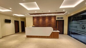 Un espace d’accueil au design moderne, comprenant un comptoir de réception, un mur revêtu de panneaux en bois et une horloge murale.