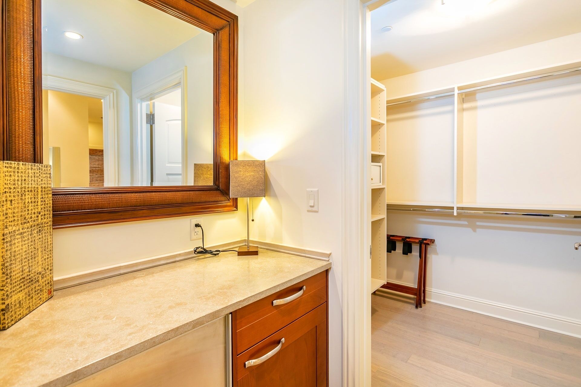 A bathroom with a wooden vanity, a mirror, and a towel rack.
