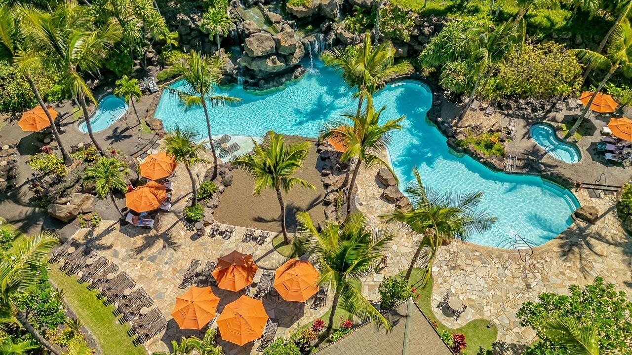A resort with multiple swimming pools, lounge areas with umbrellas, and palm trees.