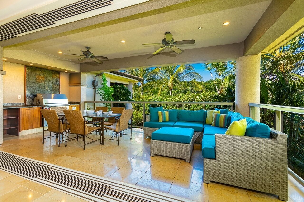 A modern kitchen with a dining area, a large sofa, and a ceiling fan.