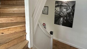 Een houten trap met een witte leuning en een zwart-wit foto aan de muur.