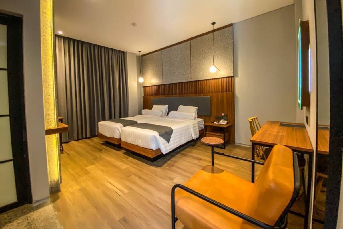 A modern hotel room with a large bed, a wooden desk, and a chair.