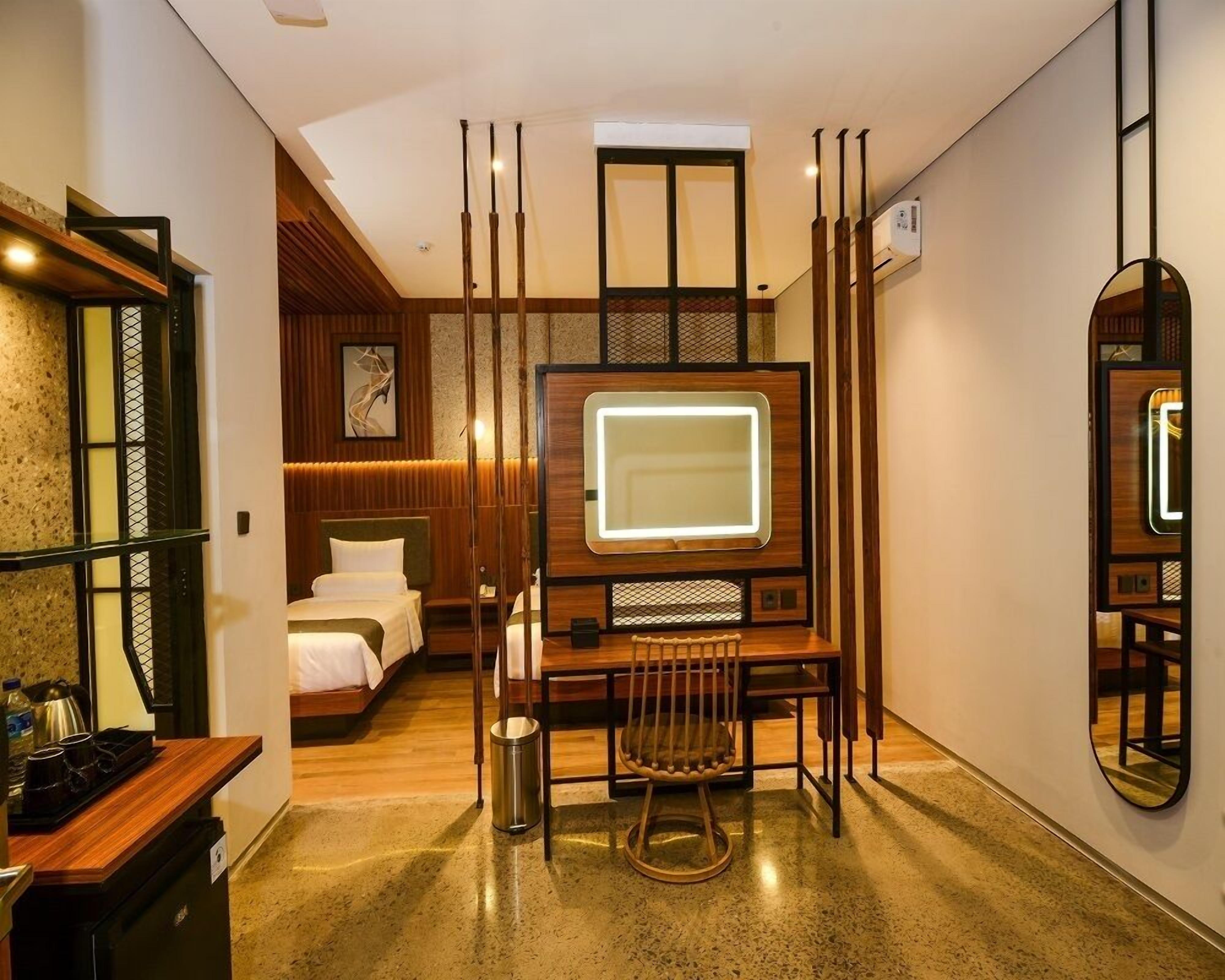 Une chambre d’hôtel comprenant un lit, un bureau avec une chaise, une télévision, un miroir et une petite kitchenette.