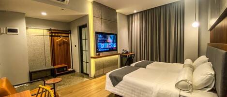 A modern hotel room with a large bed, a desk, a television, and a seating area.