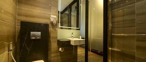 A modern bathroom with a toilet, sink, and glass shower enclosure.