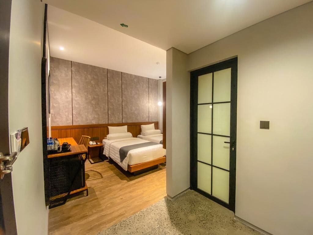 A hotel room with a bed, bedside table, and a wardrobe.