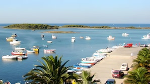 A marina with numerous boats docked, a sandy beach, and a small island in the distance. - Emerald Residence Sleeps 12 With Sea View (Porto Cesareo)