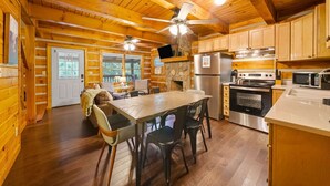 Ein Holzblockhaus-Interieur mit Essbereich, Küche und Kamin aus Stein.