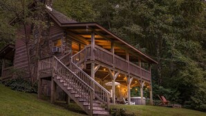 Ein rustikales Blockhaus mit einer Holztreppe, die zu einer Veranda führt.