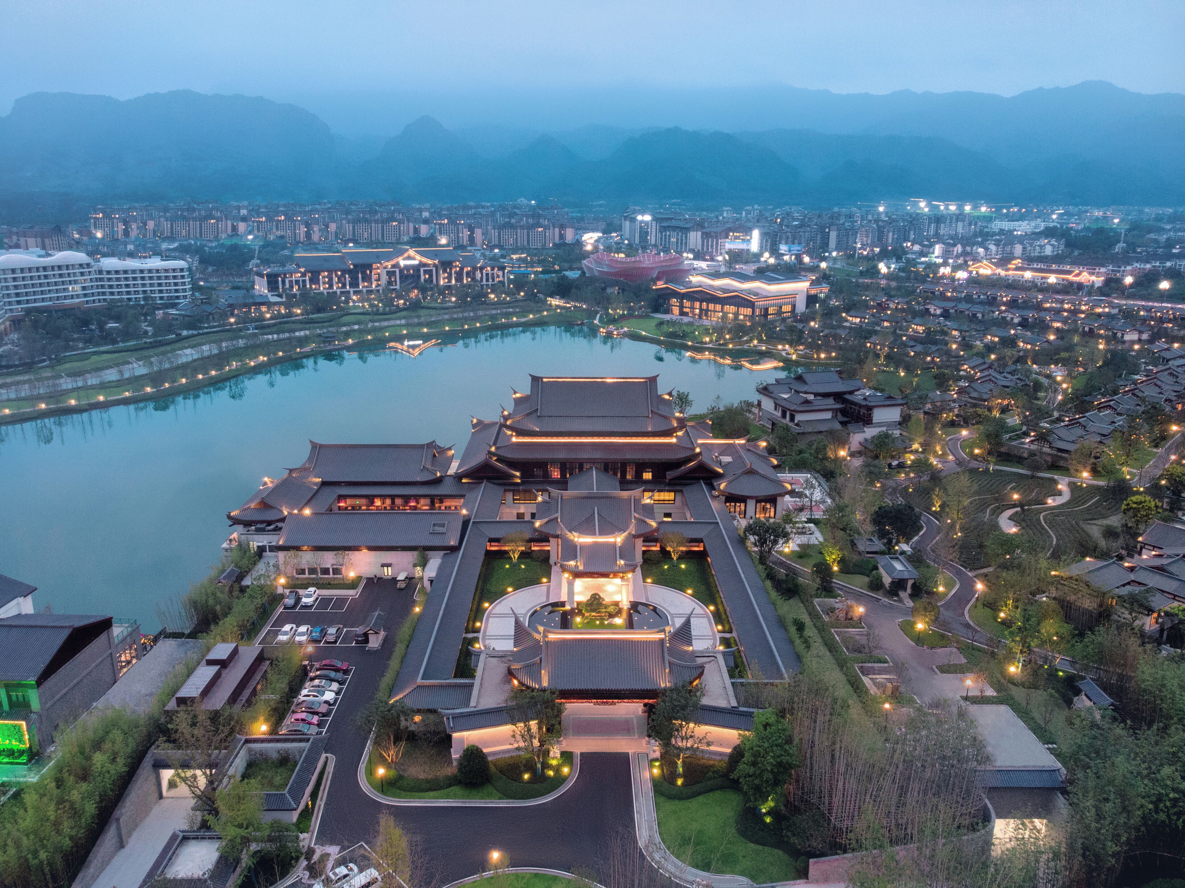 An aerial view of a traditional building complex with multiple interconnected structures, a central courtyard, and a surrounding moat.