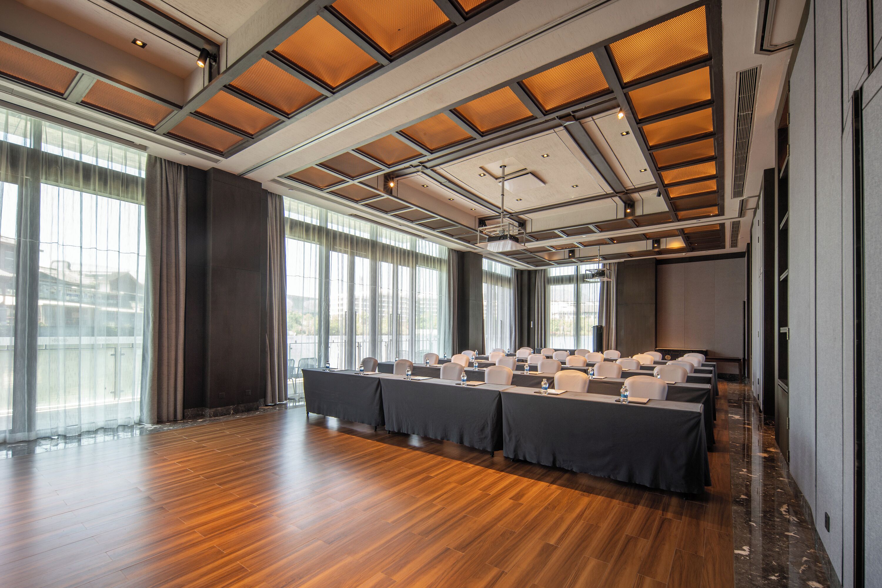 A conference room with a long table, chairs, and a projector screen.