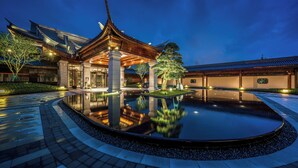 Un bâtiment traditionnel, agrémenté d’un bassin d’eau décoratif à l’avant, et entouré d’un aménagement paysager soigné.