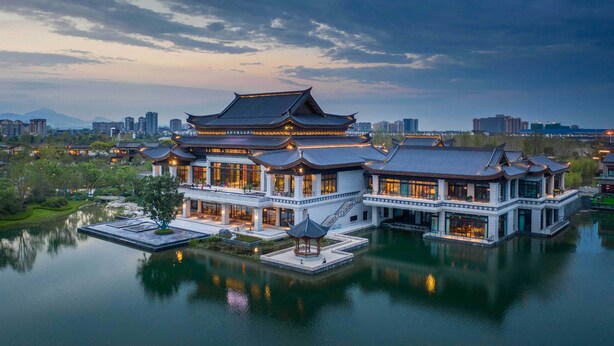 Un bâtiment traditionnel chinois, à plusieurs niveaux, dont l’image se reflète dans l’eau.