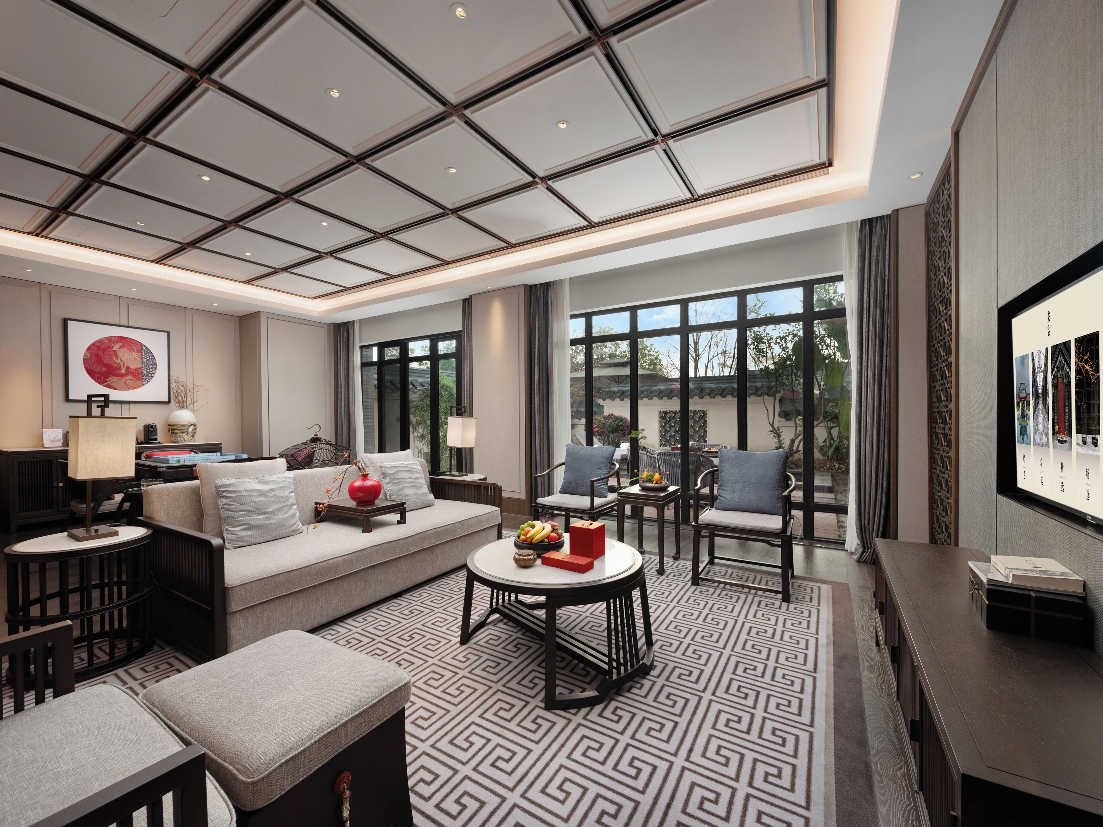 A spacious living room with a sofa, chairs, a coffee table, and a large window offering a view of the outdoors.