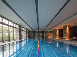 An indoor swimming pool with clear glass walls, a tiled floor, and a view of greenery outside. - Song Hotel Chengdu Qingcheng  (Chengdu)
