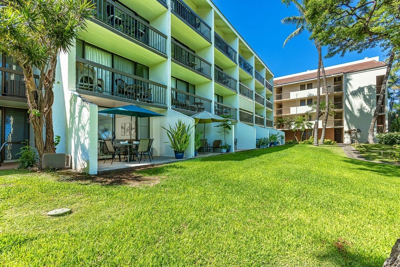 Ein mehrstöckiges Hotel mit Balkonen, Sitzgelegenheiten im Freien und einem gepflegten Rasen.