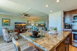 A modern kitchen with granite countertops, stainless steel appliances, and a dining area with a large island. - Maui Parkshore by Coldwell Banker Island Vacations (Kihei)