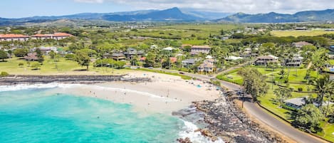 A coastal town with a beach, houses, and mountains in the background.