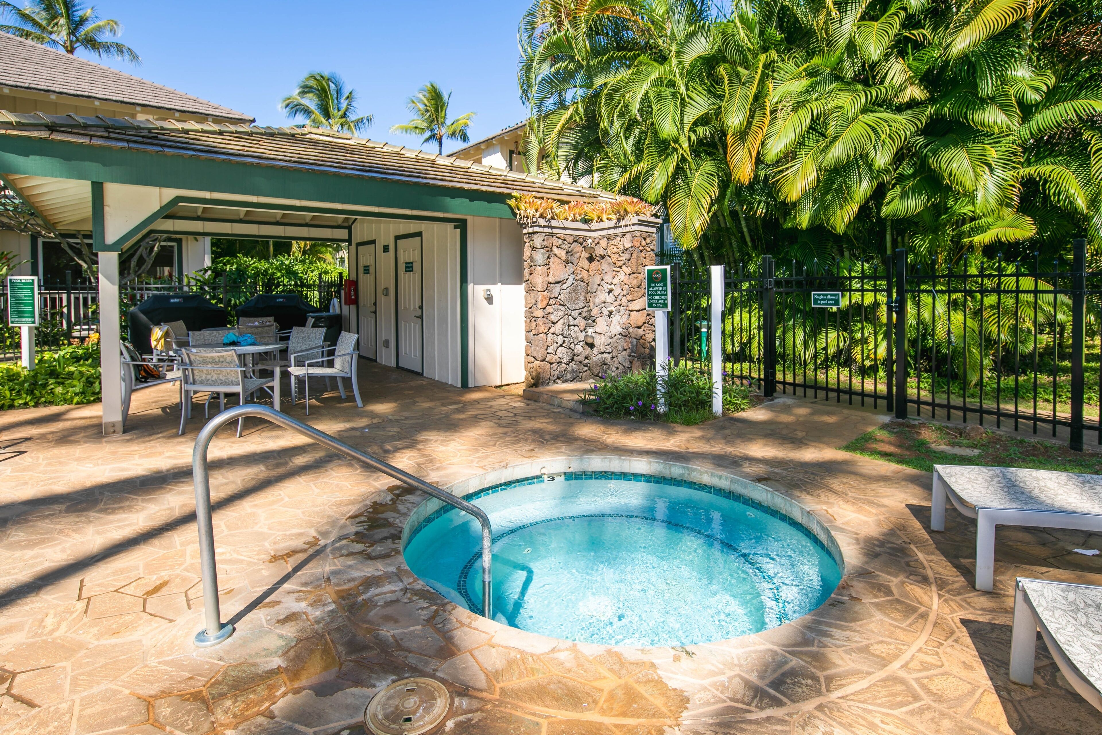 A swimming pool with a stone deck, surrounded by lounge chairs and a covered patio area with outdoor seating.