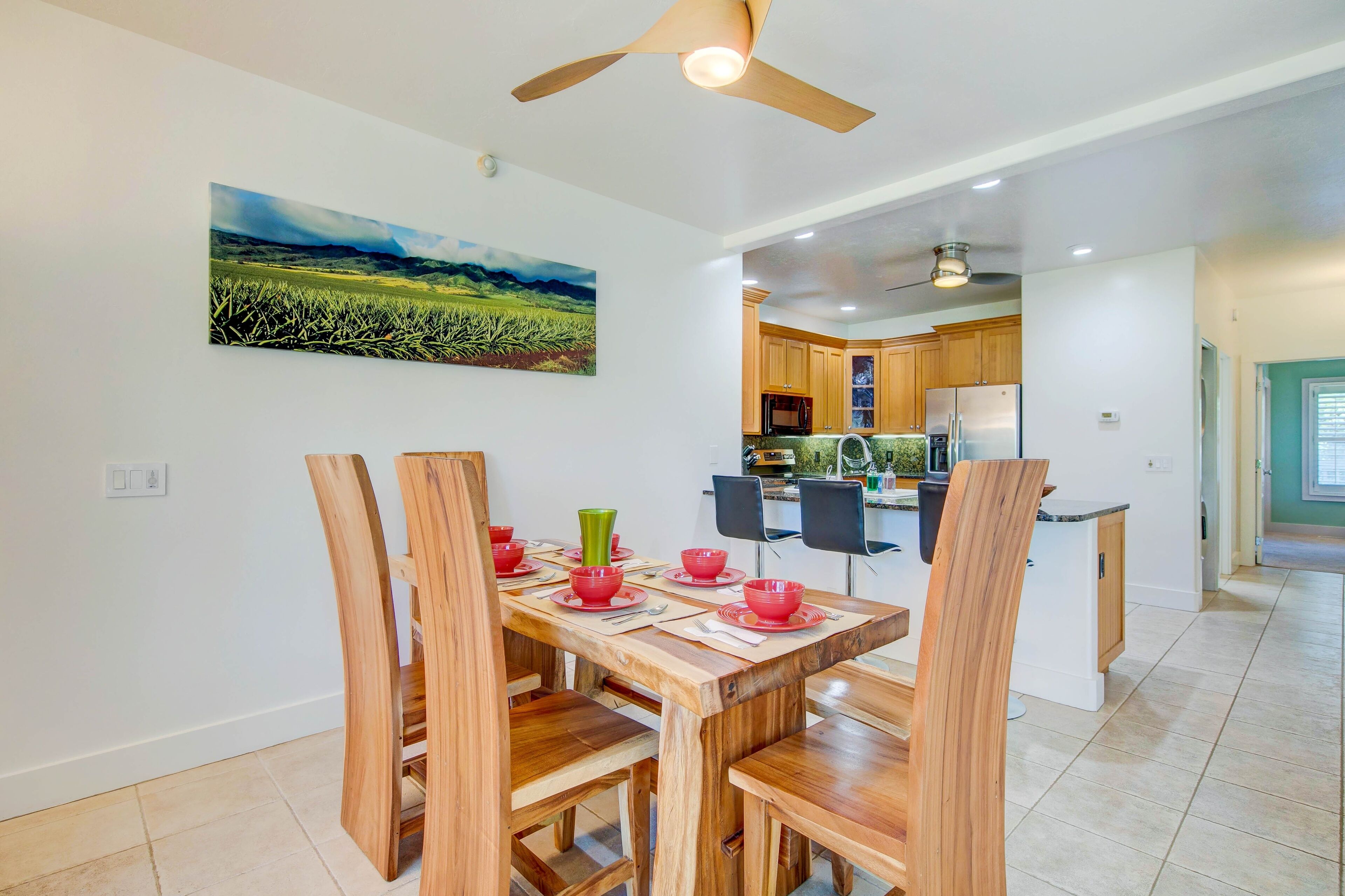 Une cuisine moderne avec des meubles en bois, un îlot central et un coin repas comprenant une table et des chaises en bois.