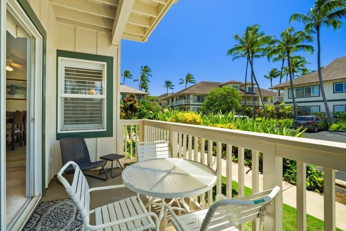 A balcony with a white railing, a round table, and four chairs.