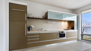 Une cuisine moderne avec des meubles en bois, un four en acier inoxydable et une grande fenêtre donnant sur l’extérieur.