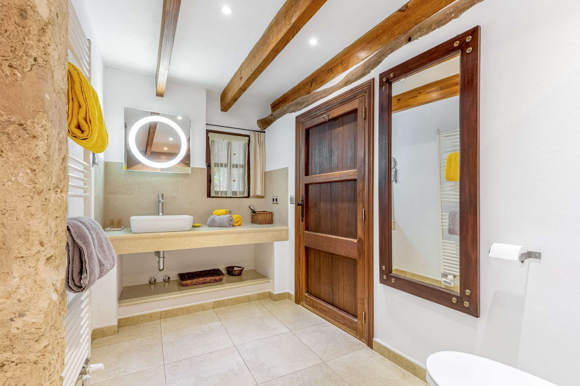 Une salle de bain avec une porte en bois, un lavabo, un miroir et un porte-serviettes.