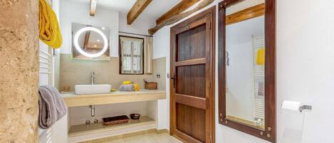 Une salle de bain avec une porte en bois, un lavabo, un miroir et un porte-serviettes.