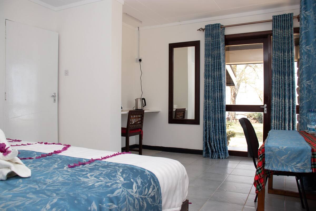 Un dormitorio con cama, escritorio, silla, mesa y ventana con cortinas.