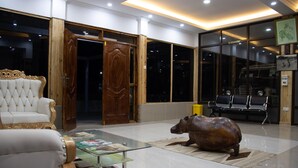 Un hall d’entrée spacieux, agrémenté d’un canapé blanc moelleux, d’une table basse en verre et d’une grande statue de bronze représentant un rhinocéros.
